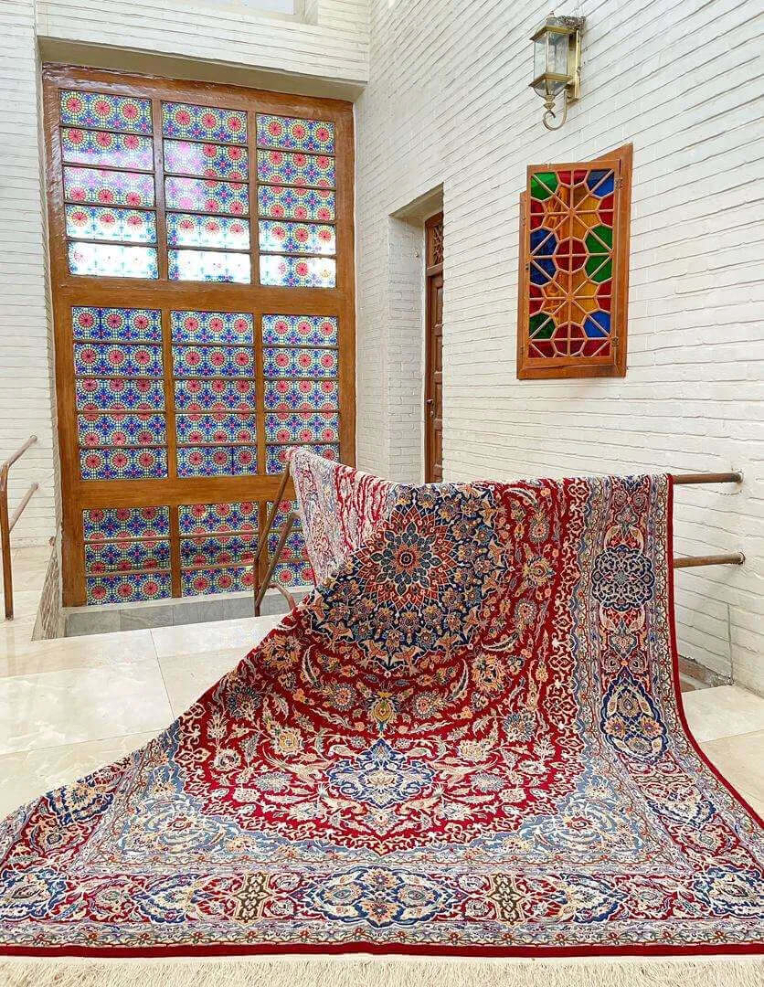 Isfahan Persian carpet spread out on the floor showcasing its red and blue design