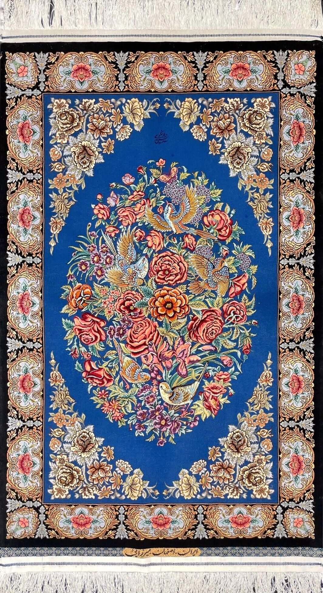 "Hand-knotted Isfahan Persian rug featuring an oval floral bouquet and flying birds on a deep blue silk base."