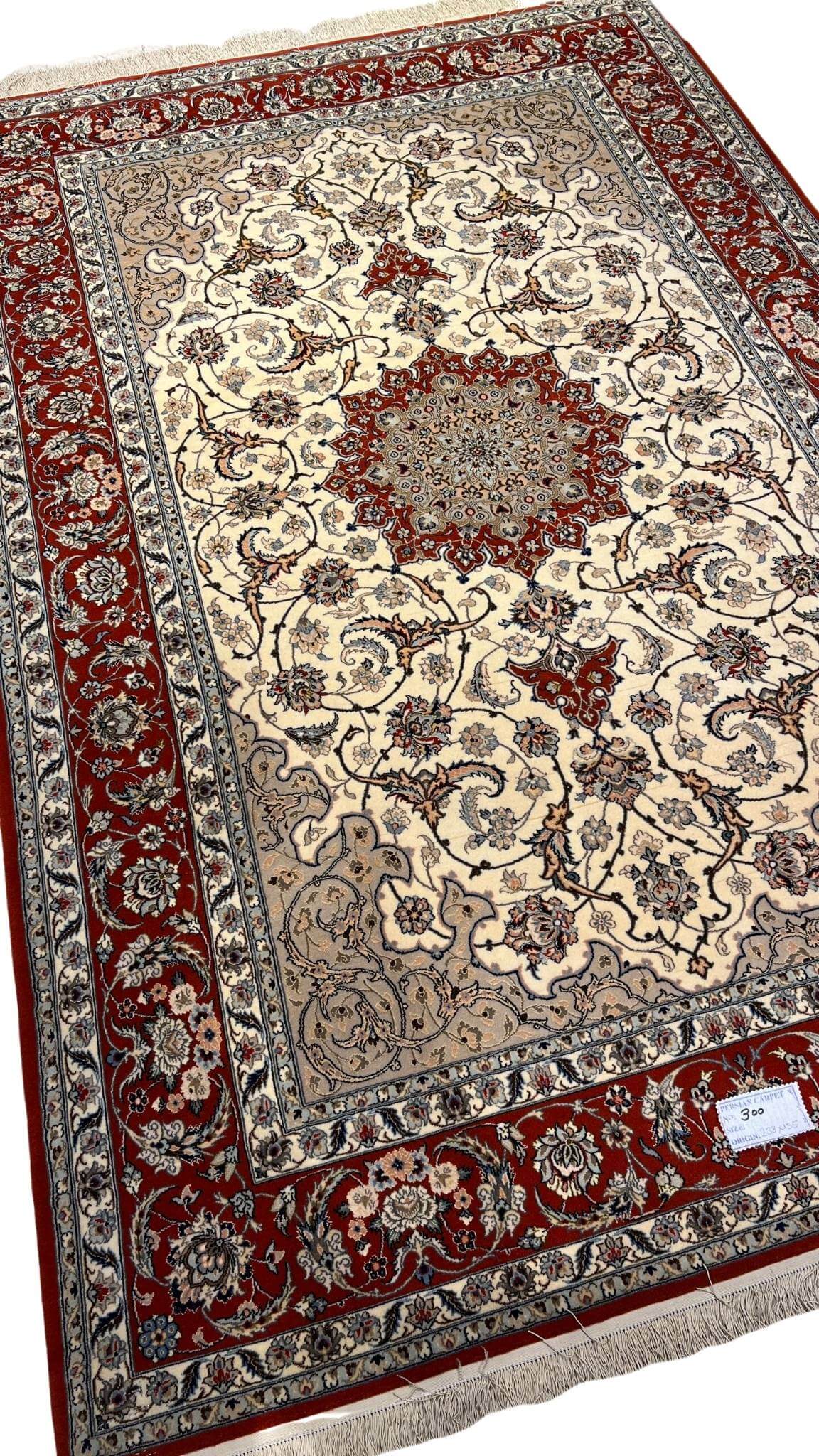 "Exquisite hand-knotted Persian rug from Isfahan, featuring luxurious silk and wool blend with a detailed red and ivory pattern. This 235 cm x 155 cm (7.7 ft x 5.1 ft) rug boasts 810,000 knots per square meter. Perfect for adding a touch of elegance to any room, this authentic Persian rug is available for online purchase with only one in stock."
