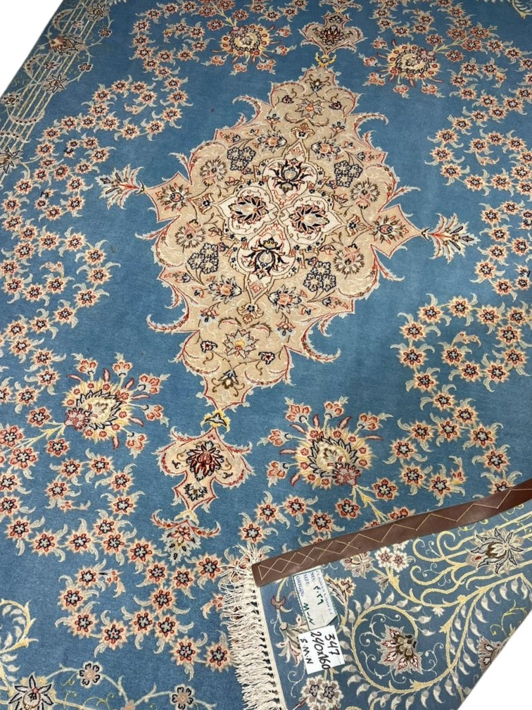 Hand-knotted Persian rug featuring intricate floral details on a blue base.
