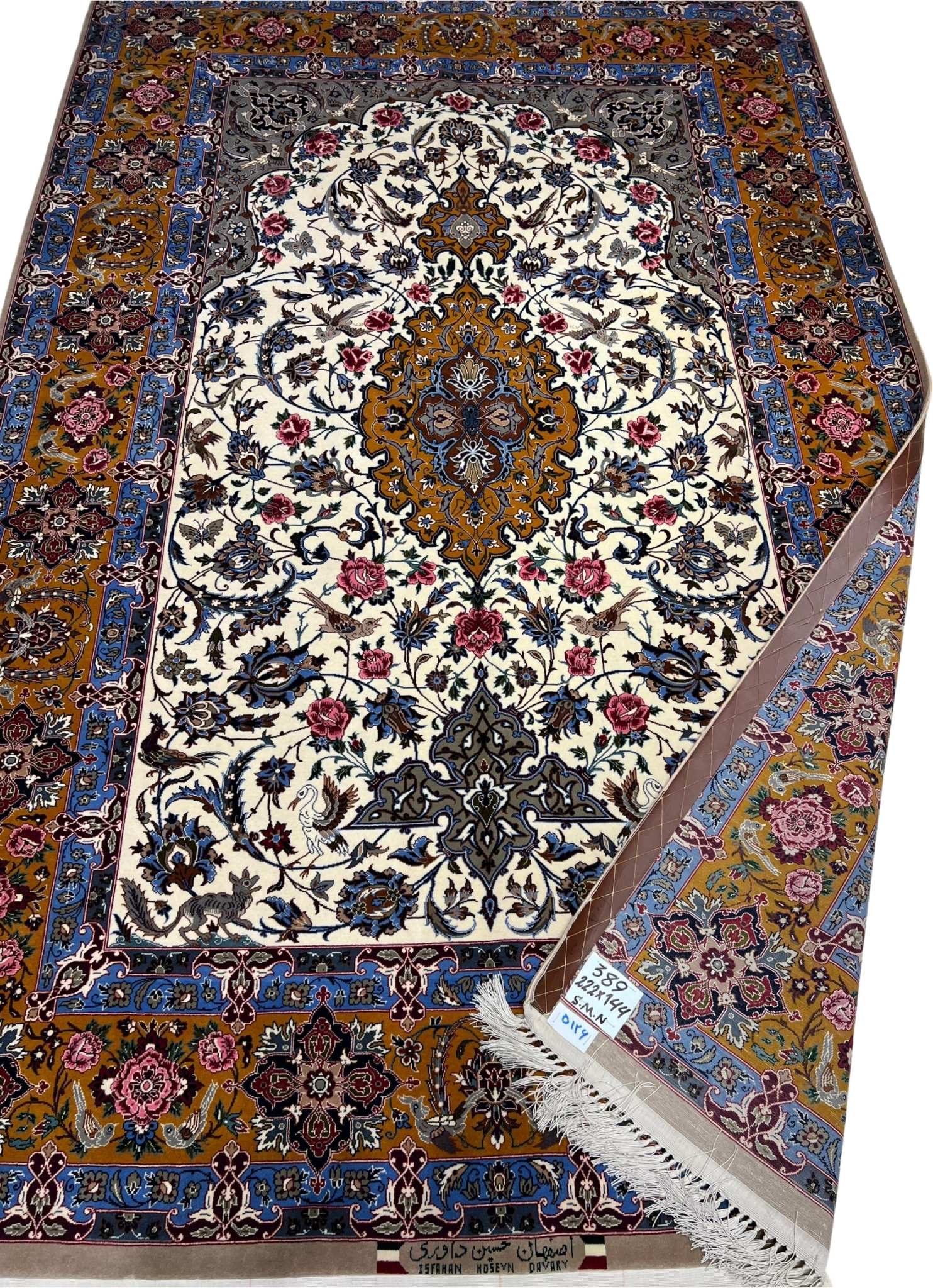 Hand-knotted wool and silk rug in ivory, royal blue, and gold tones.
