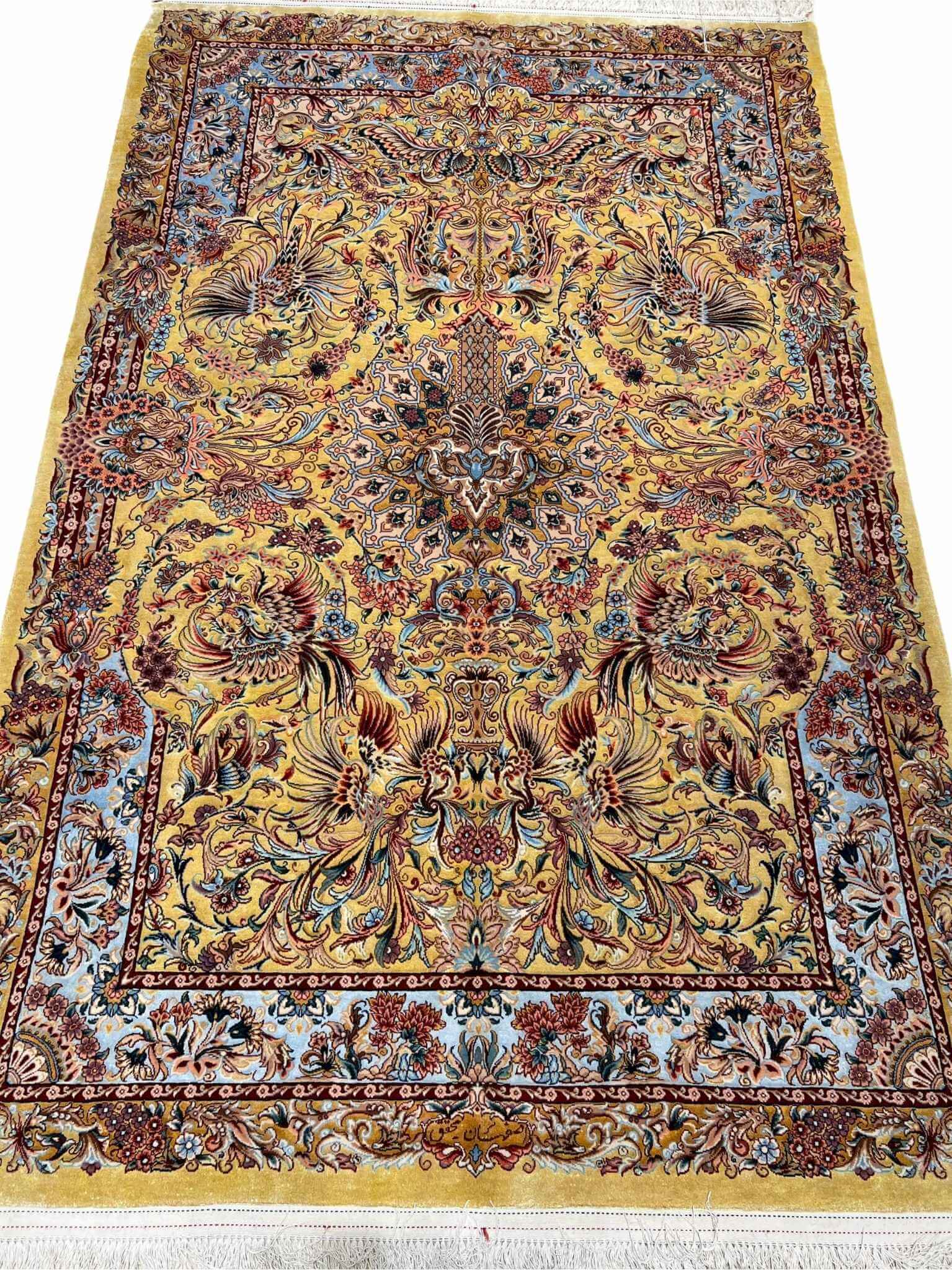 "Handwoven Isfahan Persian rug with golden phoenix design and intricate floral medallion, crafted from silk and wool."
