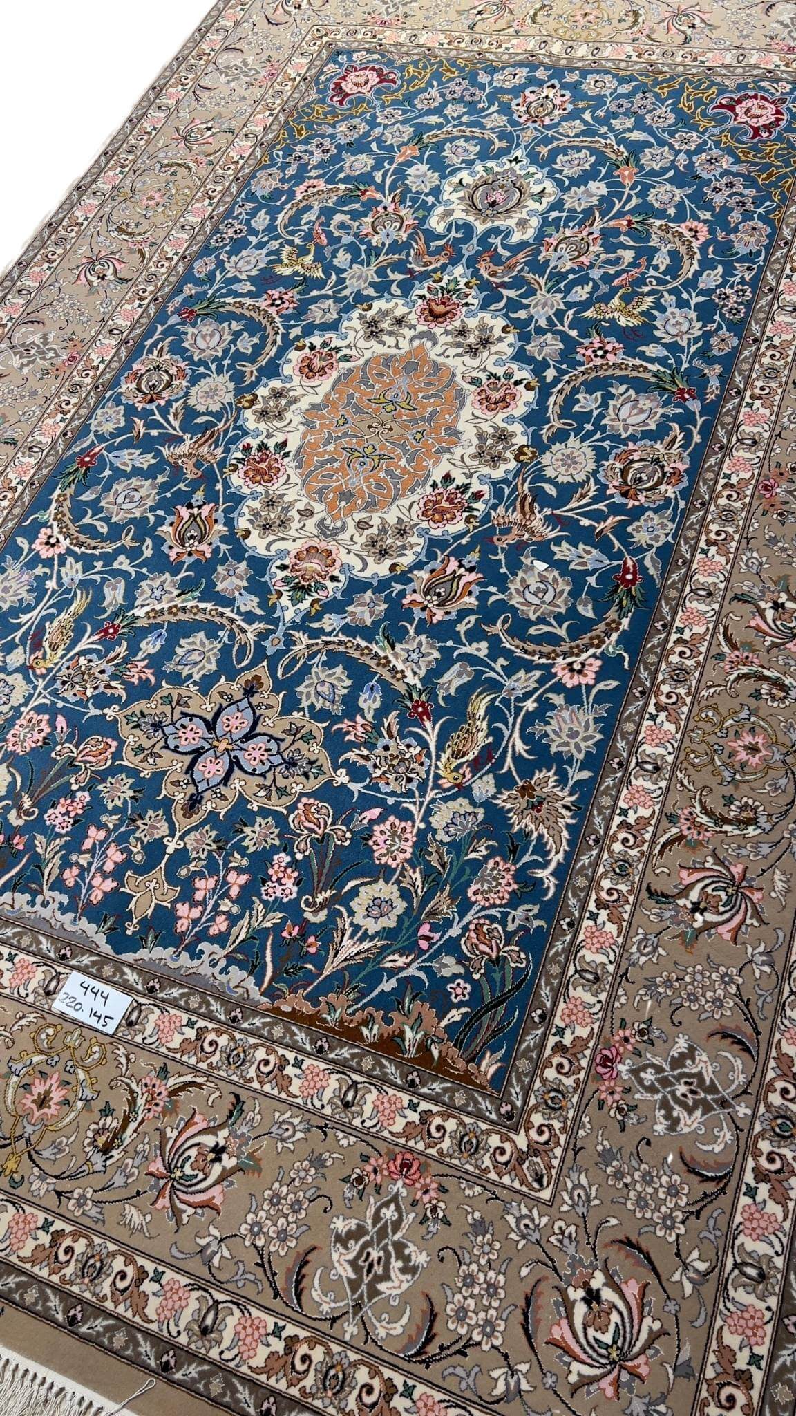 Persian rug featuring floral motifs on a blue background.
