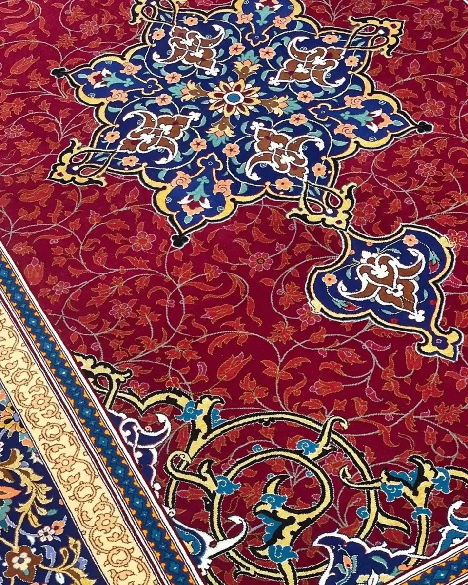 Handcrafted Persian Isfahan Rug - Close-up angle of a Persian rug showing detailed floral motifs and knot work on a vibrant red background with intricate borders in blue and gold.

