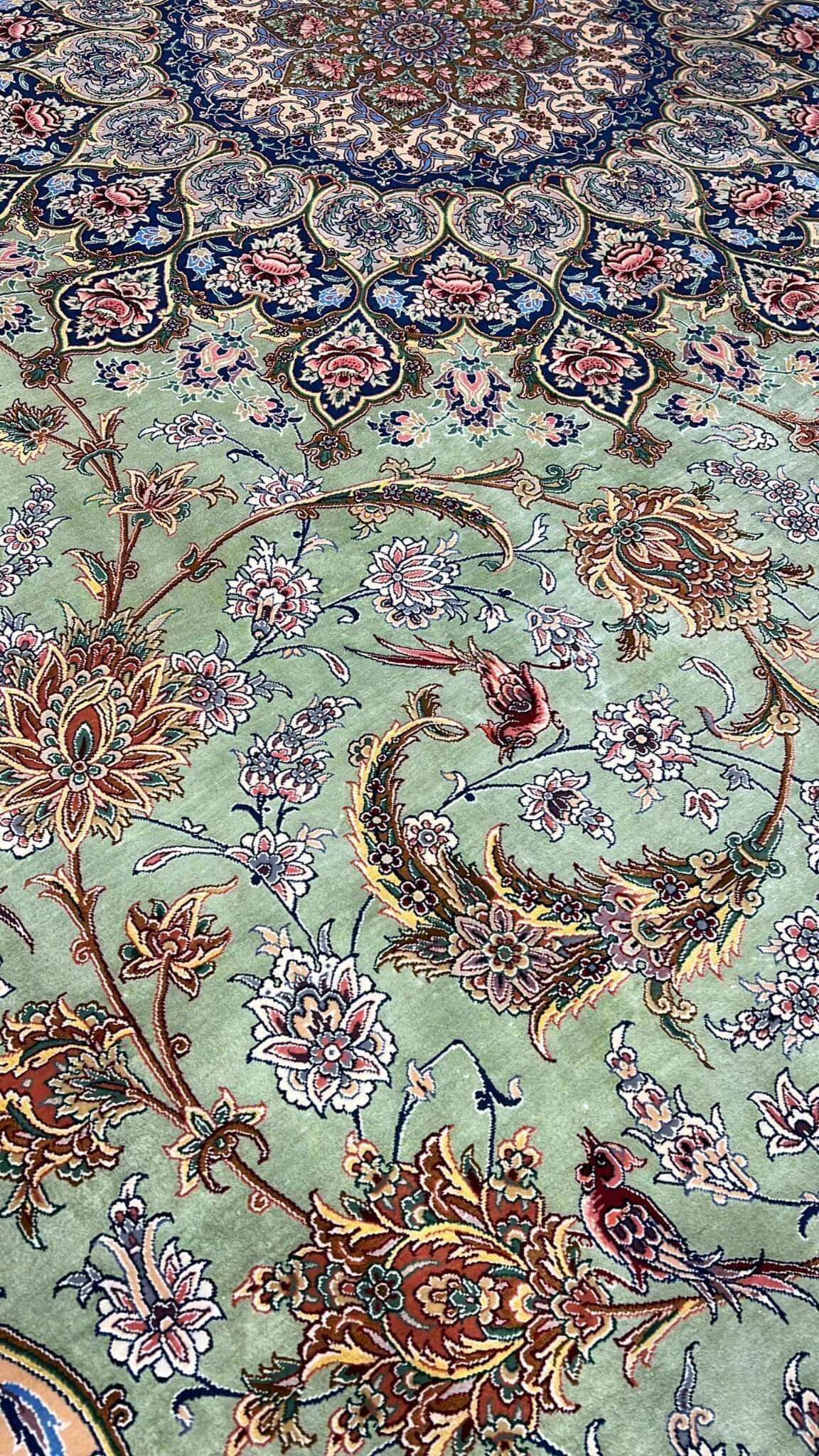 "Close-up of the light green silk field and detailed floral motifs on the Persian rug."