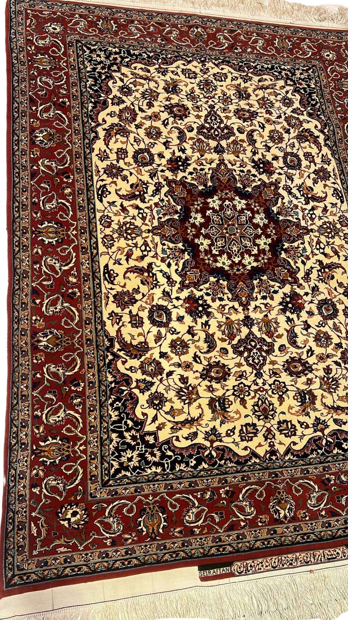 "Detailed view of the medallion design on a Seirafian Persian carpet, showcasing hand-knotted craftsmanship in red and beige tones."
