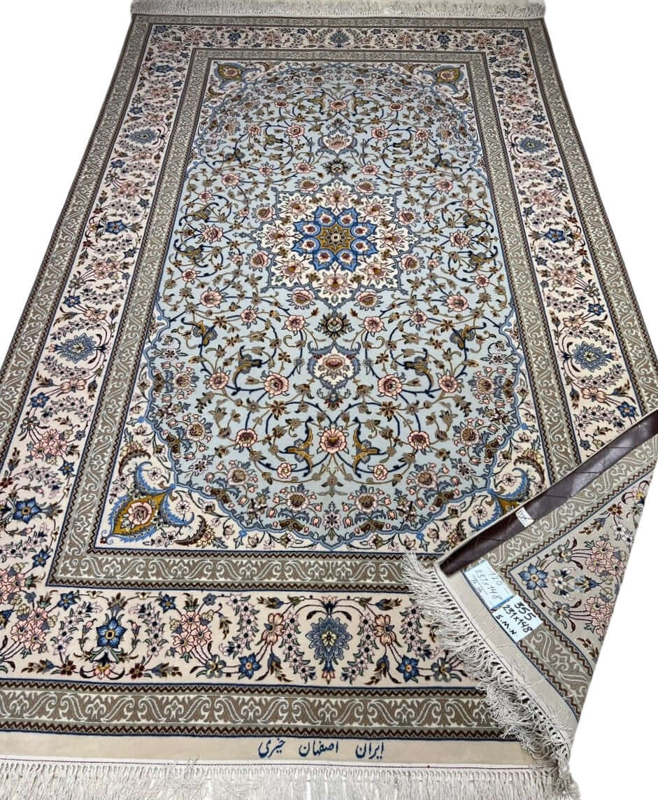 Hand-knotted Isfahan rug with a blue base and intricate floral medallion.

