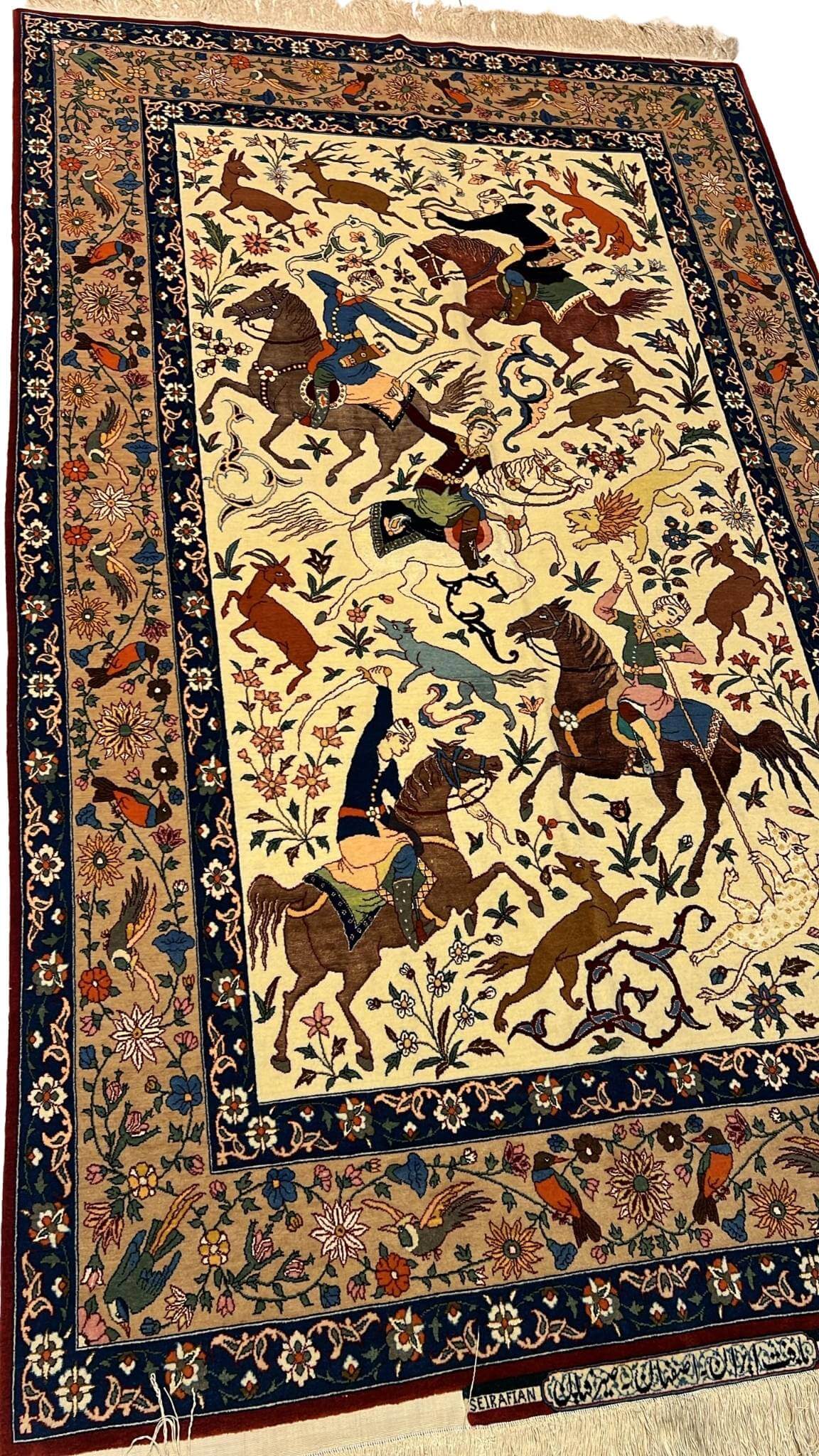 Detailed shot of a silk and wool Ahmad Seirafian rug, featuring hunting scene motifs and natural-dyed colors.
