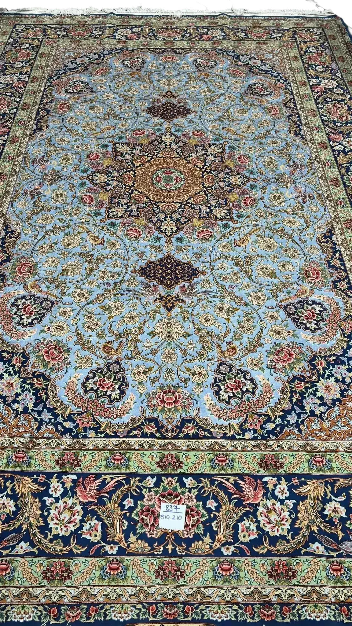 Light blue silk carpet with intricate oriental patterns in green and red hues