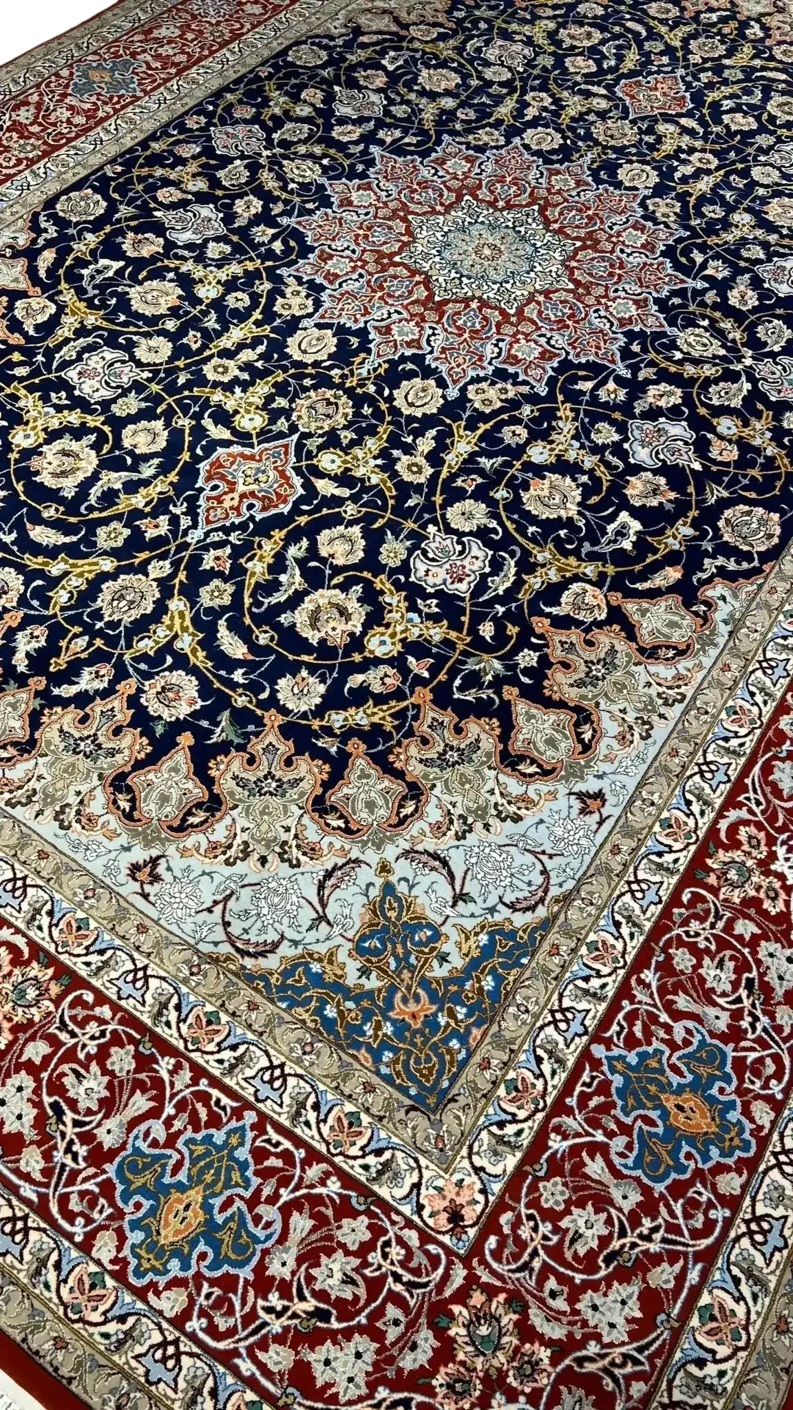 Close-up of Central Medallion on Isfahan Persian Rug – A detailed view of the central medallion on a Persian rug, showcasing vibrant red, blue, and ivory floral motifs, surrounded by intricate curving patterns, meticulously hand-knotted.

