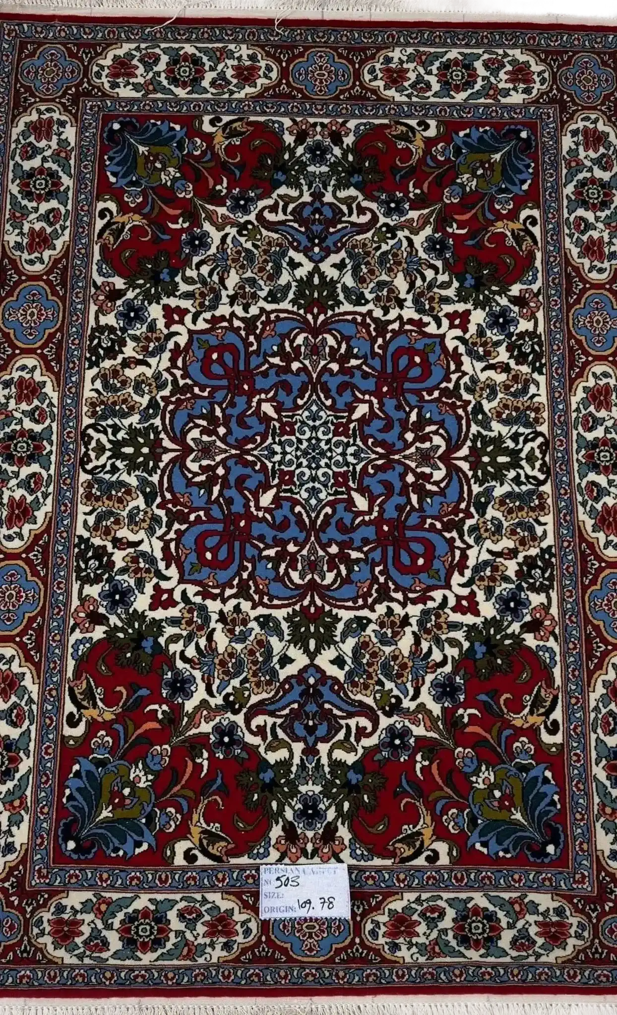 "Hand-knotted Persian rug with intricate floral and geometric designs in red, blue, and cream colors, crafted from wool and silk, showcasing traditional Isfahan craftsmanship, perfect for luxury home decor."






