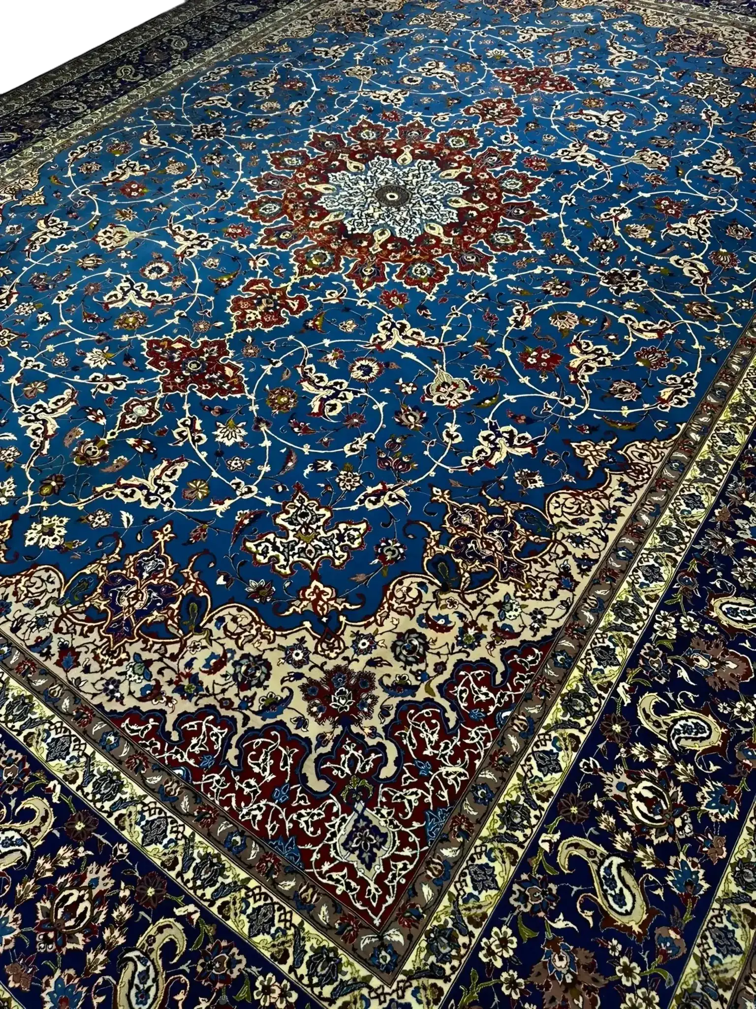 Detailed View of Central Medallion on Blue Persian Rug – A close-up shot of the elaborate central medallion on a Persian rug, showcasing intricate red, ivory, and blue floral designs with fine craftsmanship in the weaving.

