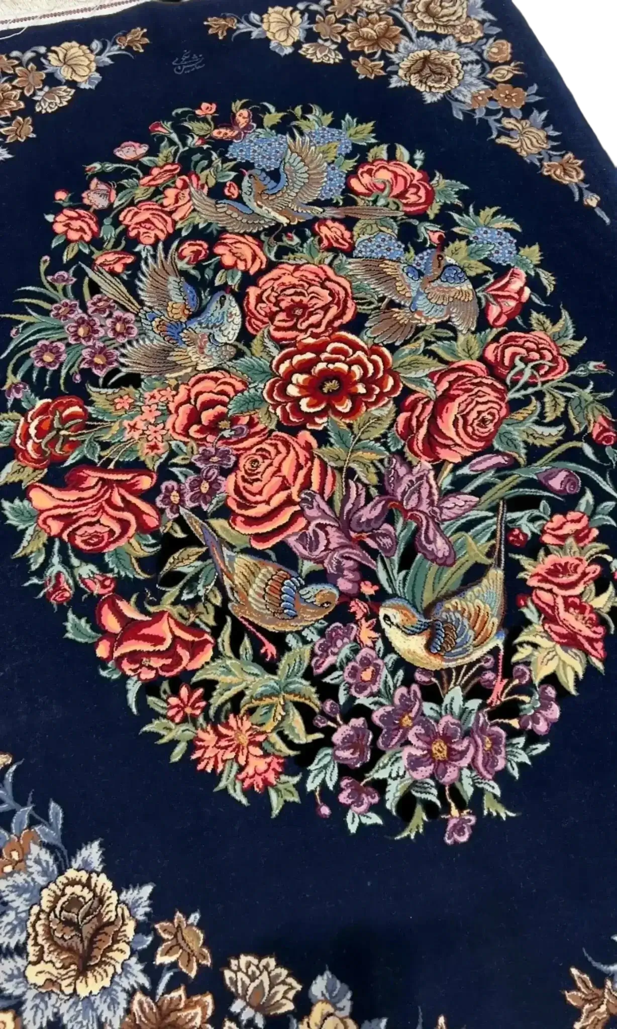 Close-up of the detailed floral embroidery on a navy Persian Isfahan rug