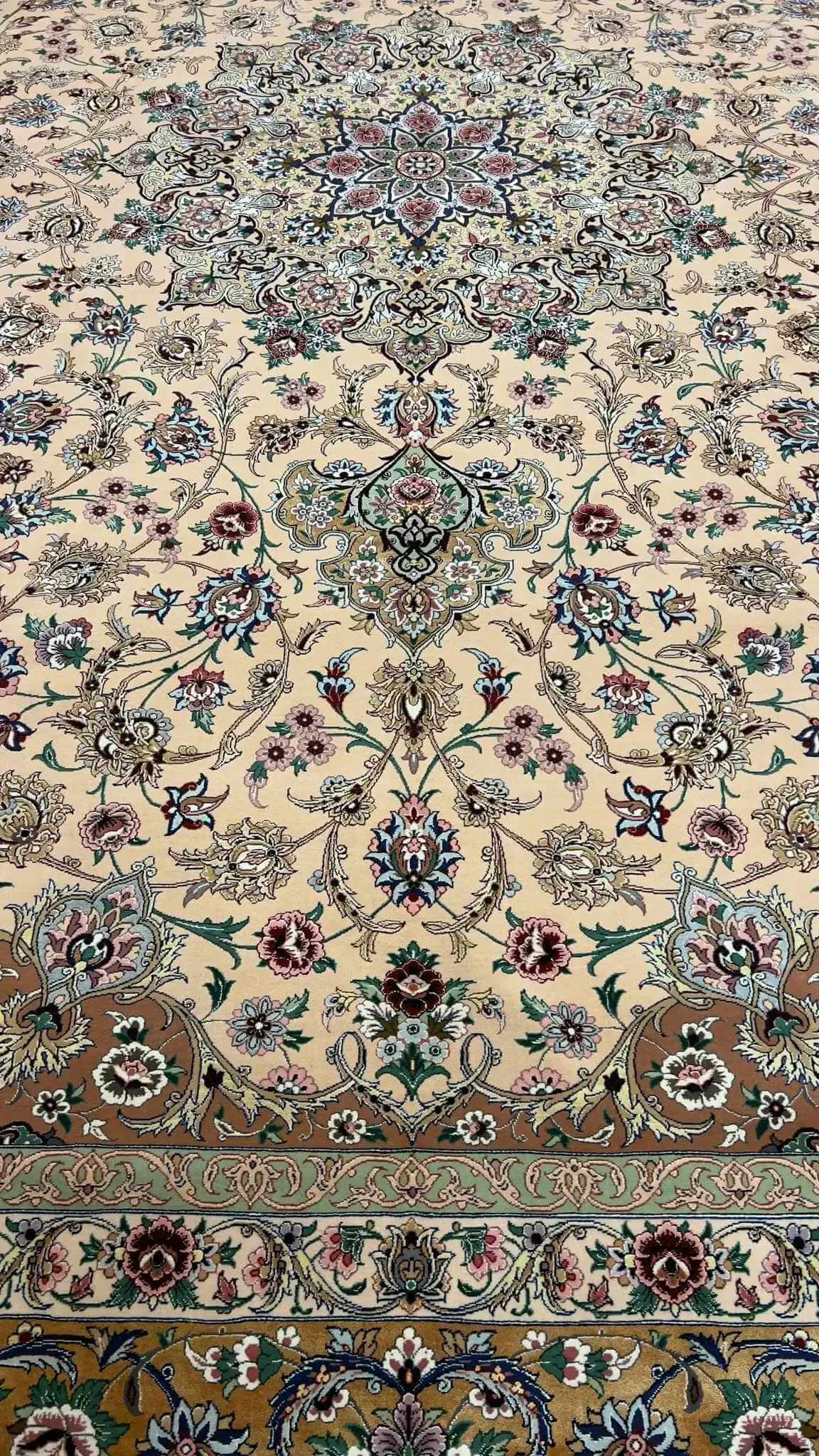 Close-up of the floral design on a beige hand-knotted Iranian rug