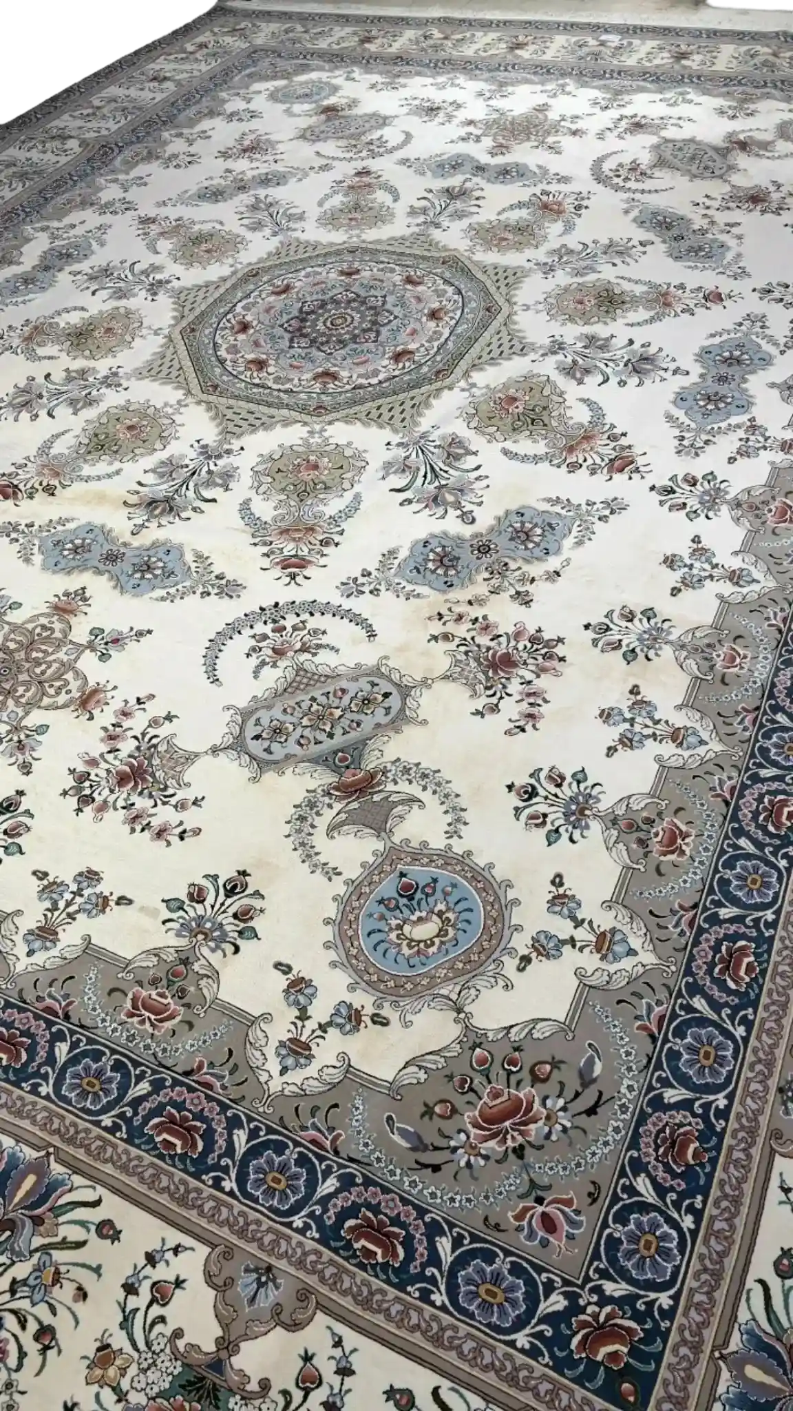 Side view of a luxurious Isfahan rug showcasing the dense knot work and the delicate floral design in shades of cream and blue.
