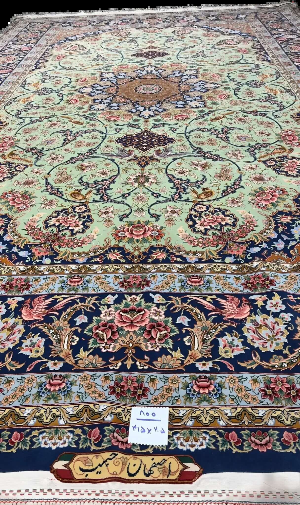 Light green Iranian handmade carpet with intricate patterns on display