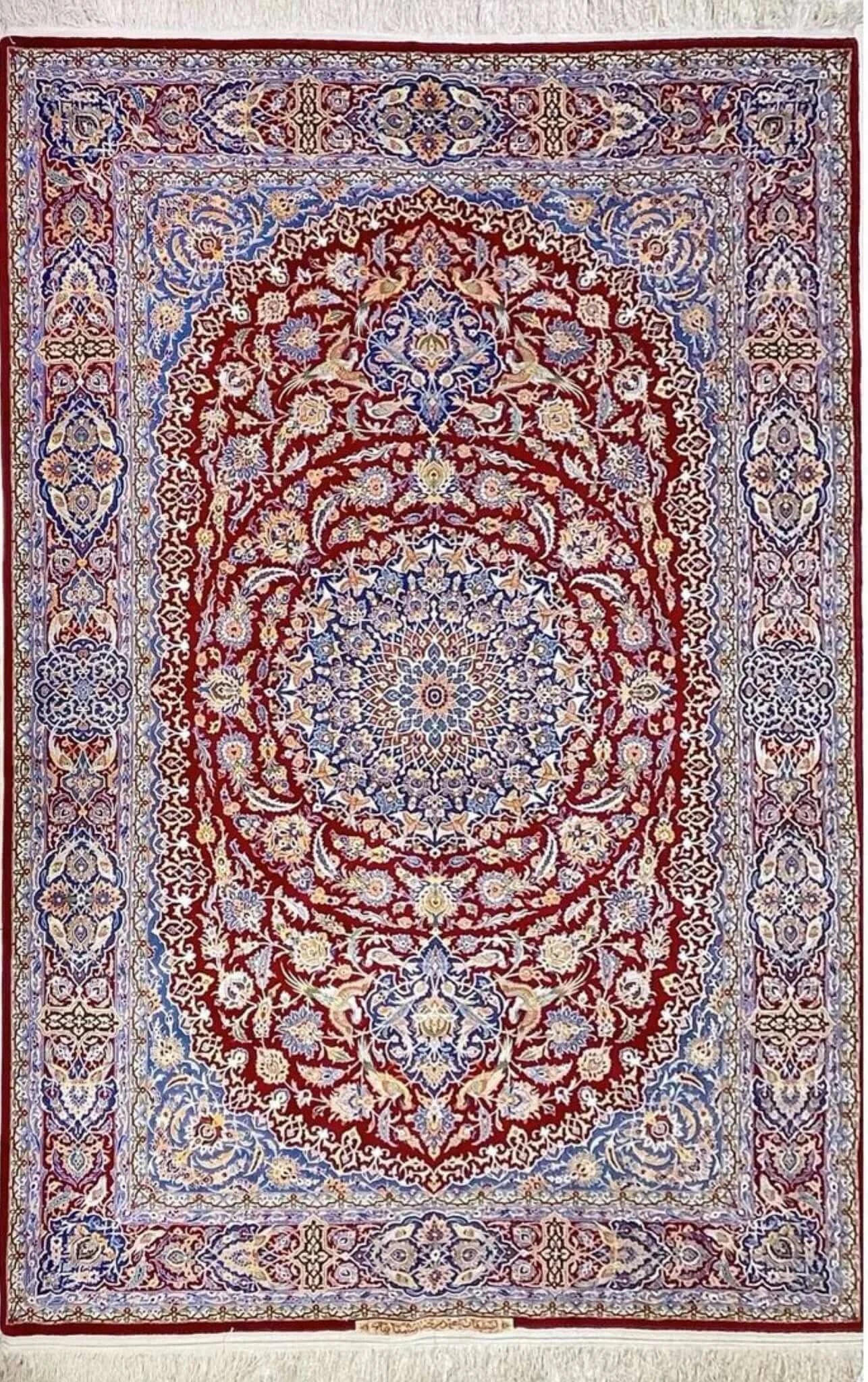 Detailed view of the Isfahan Persian carpet's central medallion with intricate floral patterns in red, blue, and ivory.

